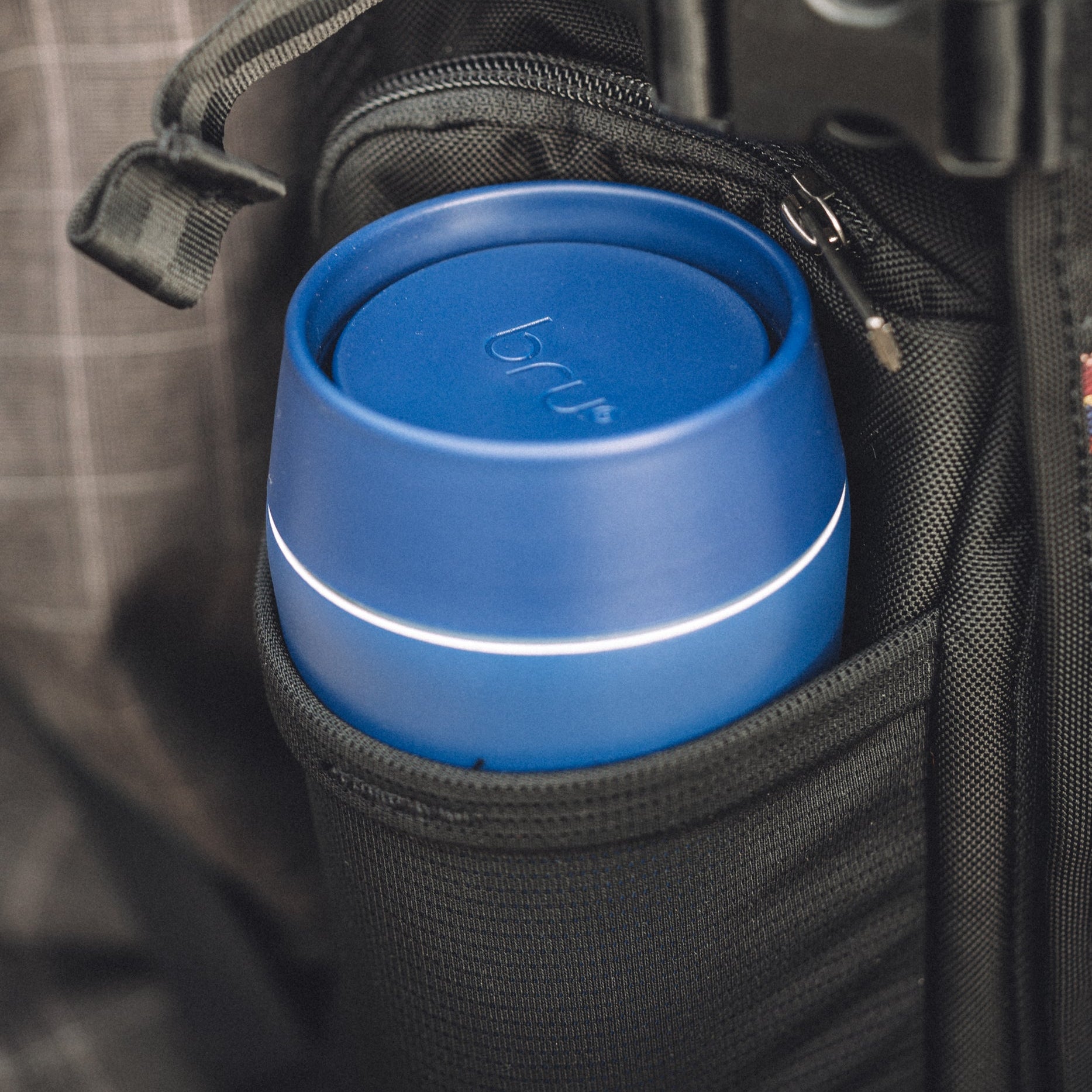 bru blue insulated travel mug sitting in the side pocket of a bag, viewed from above
