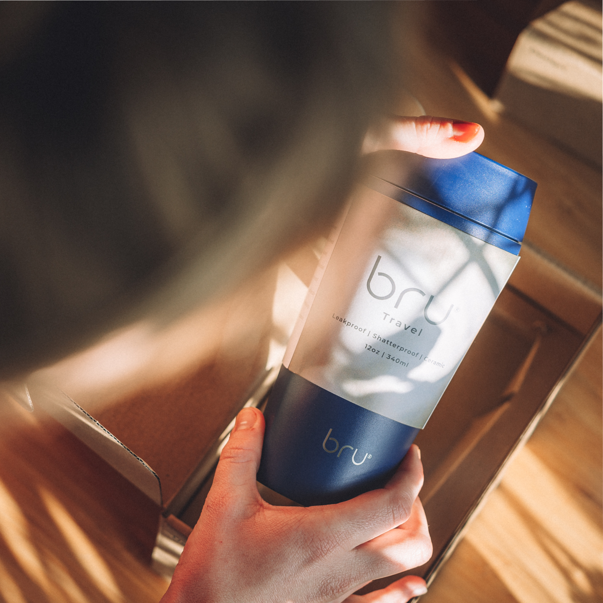 person holding bru ceramic travel mug 12oz in blue planet