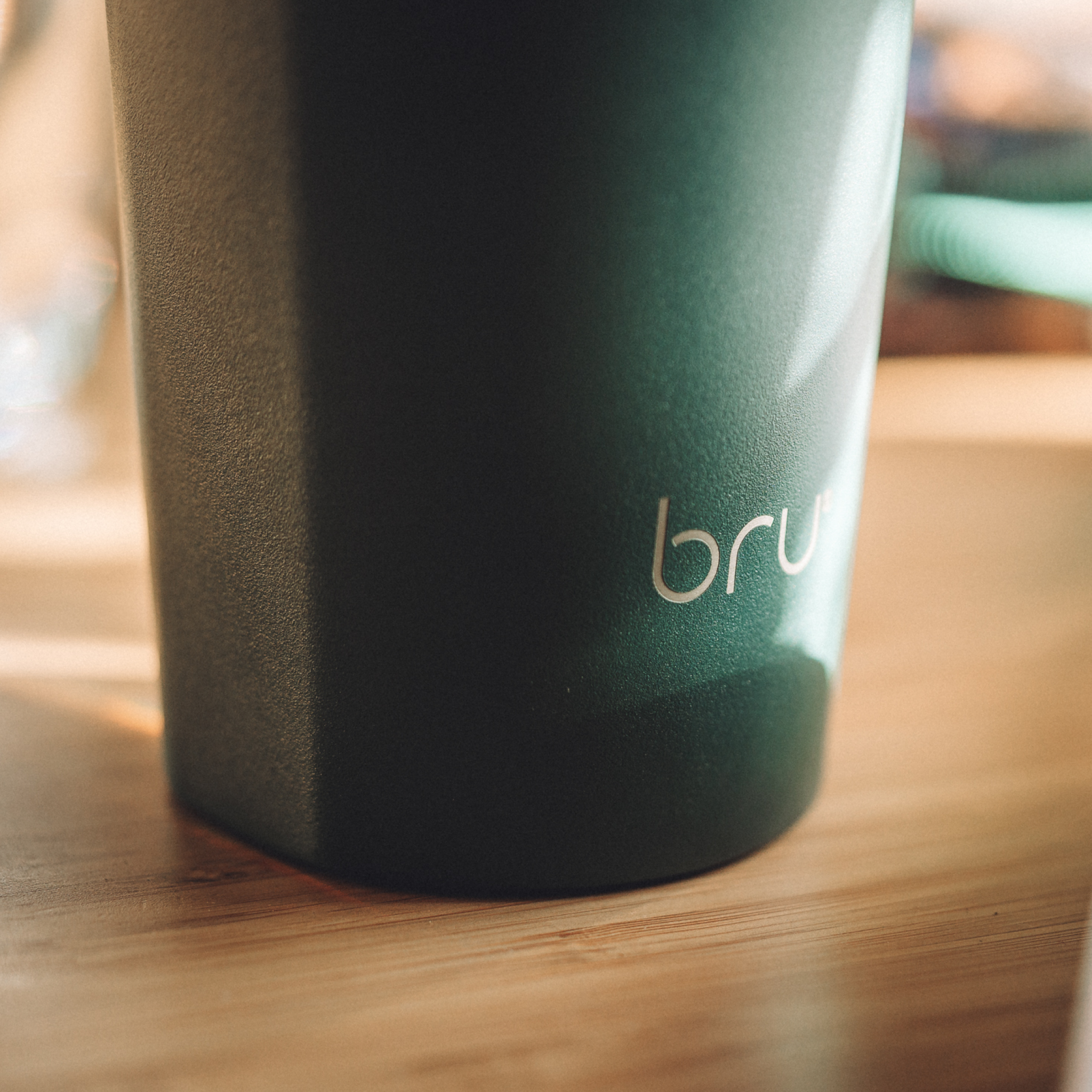 close up of bru ceramic travel mug in aranya green on wooden table
